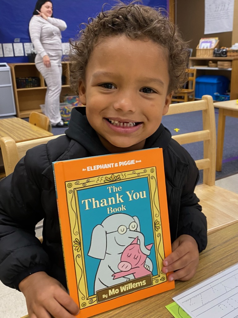Preschooler holding up The Thank You Book by Mo Willems