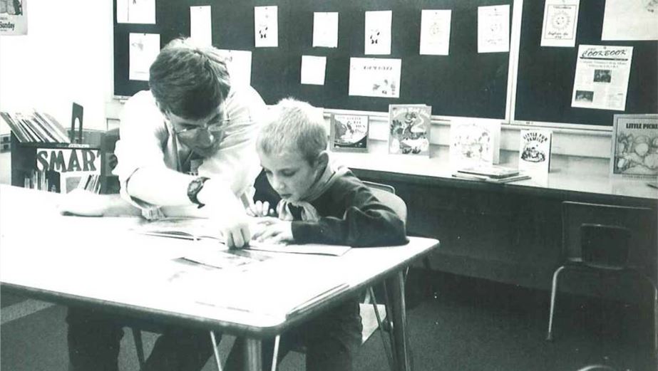Photo of Randall B. as a child reading with a SMART Volunteer