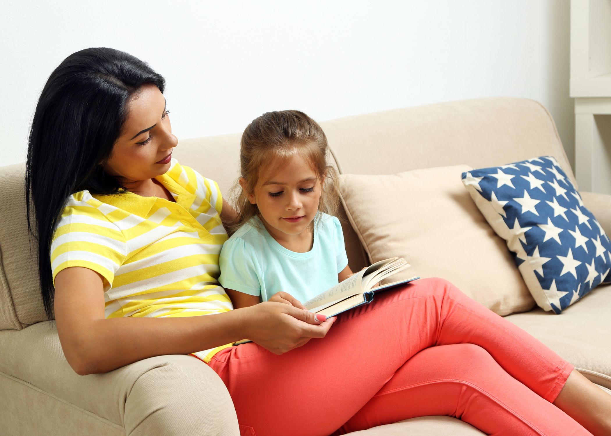 Parent reading a book with a child on a couch