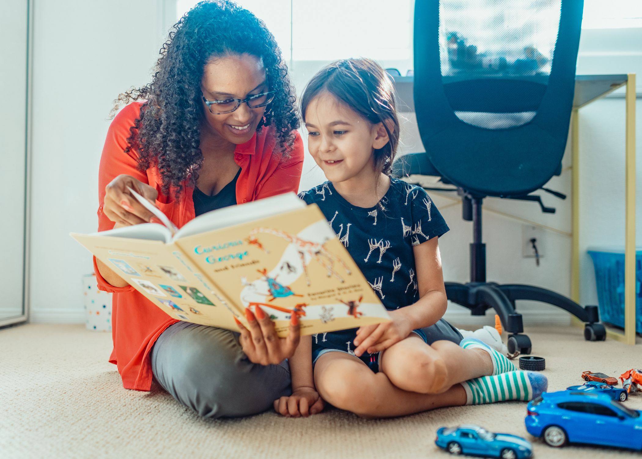 An adult reading a picture books with a child.